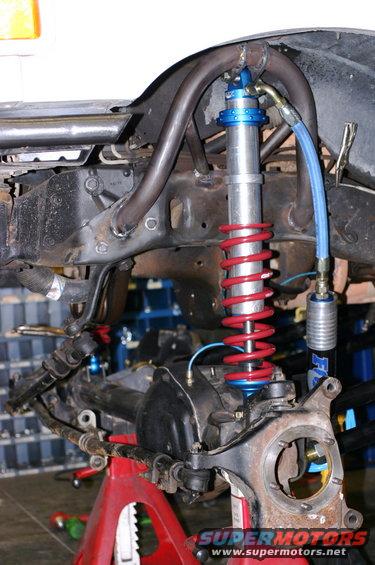 Front suspension part with red coilover shock absorber, blue adjustable top, and metal tubing