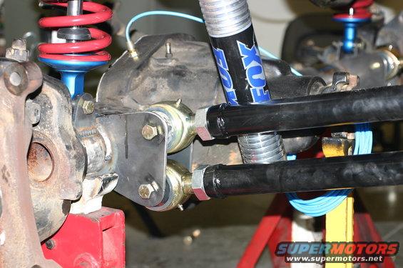 Close-up of vehicle's rear axle with Fox shocks and red coil springs