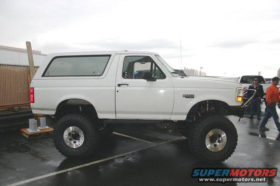 White Ford Bronco with lifted suspension and large tires, side view