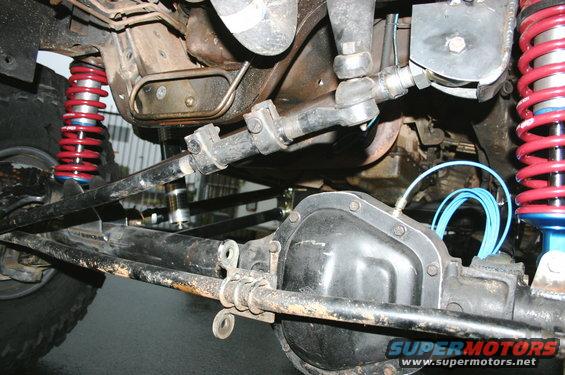 Close-up of a vehicle's front axle with red coilover shocks and steering linkage