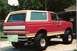 1990 Ford Bronco - This lifted Ford Bronco, painted red with tan accents, is parked outdoors near a garage and basketball hoop.