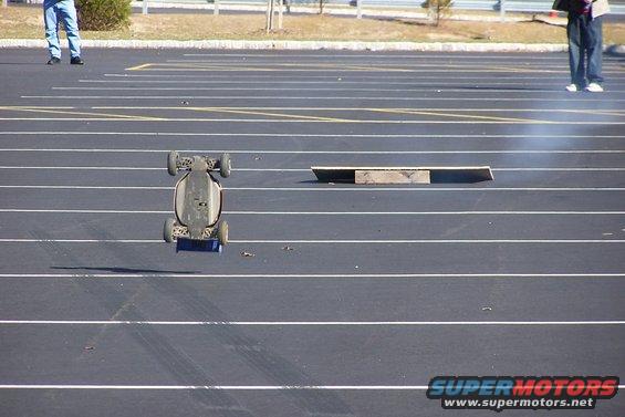 Remote-controlled car airborne, upside down, over asphalt track
