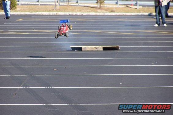 Red remote control car airborne over a ramp