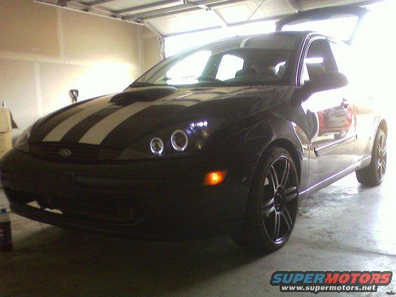 Black 2002 Ford Focus with white racing stripes and halo headlights