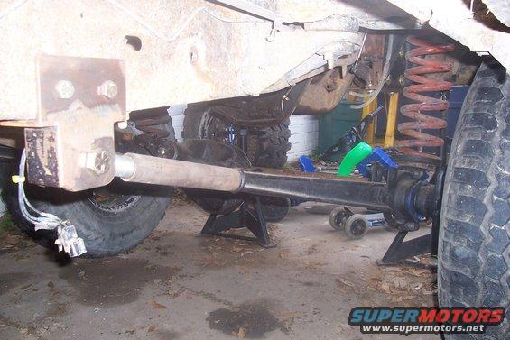 Close-up of vehicle's front axle, suspension, and frame components on jack stands