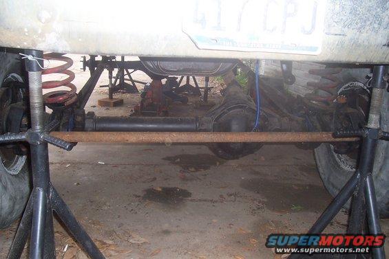 Undercarriage of a vehicle on jack stands, showing suspension and differential