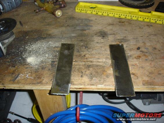Two metal plates on a wooden workbench with tools and a yellow level