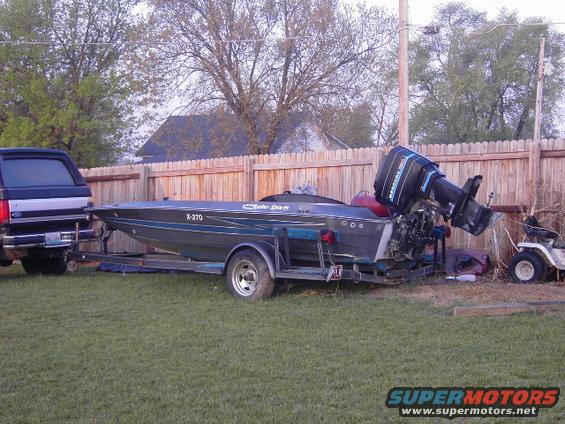 Boat with Mercury outboard motor on trailer, towed by a truck