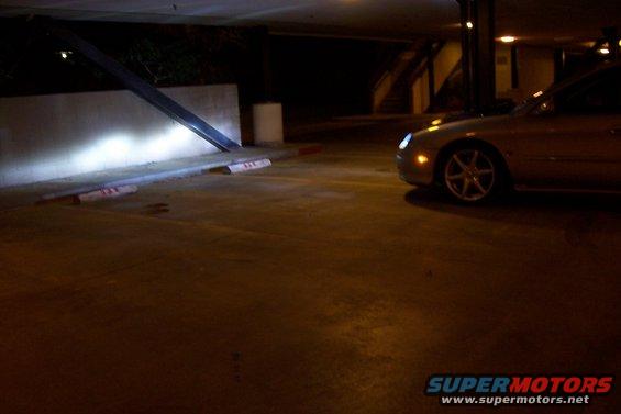 Car parked in a garage with headlights on, facing forward