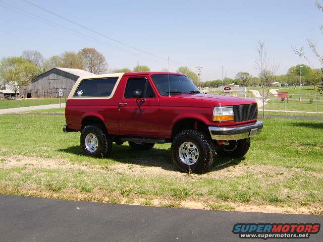 Red 1989 Ford Bronco with tan top parked on grass