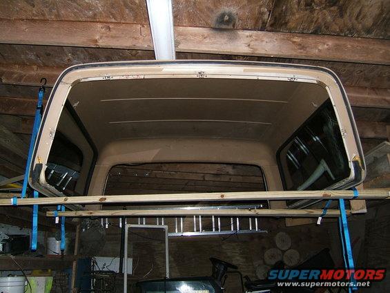 Truck cap hanging from ceiling in garage. Shows interior and side windows