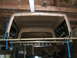 1988 Ford Bronco - A truck cap is suspended from the ceiling of a garage, awaiting installation.