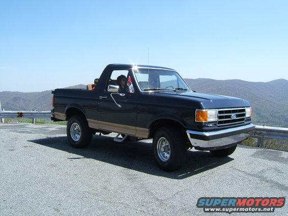 Dark blue Ford Bronco with tan trim parked on a mountain road