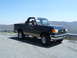 1988 Ford Bronco - A dark blue Ford Bronco with tan trim is parked on a mountain road with a scenic view.