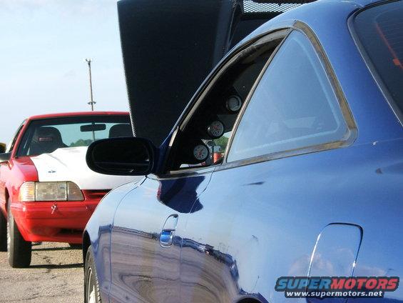 Blue car in foreground, red car with white hood behind it. Both have hoods up