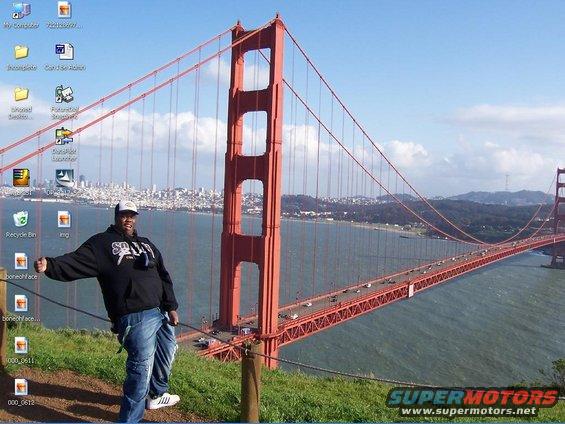 Man in hoodie and jeans poses with Golden Gate Bridge and San Francisco skyline behind him