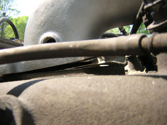Close-up of an engine intake manifold elbow with hoses and bolts visible