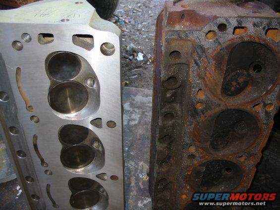 Two engine cylinder heads, one clean aluminum and one rusty cast iron, side by side