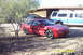 1995 Ford Probe - A red coupe with aftermarket wheels is parked on a dirt lot next to a blue and white pickup truck.