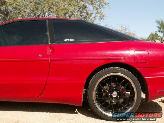 Red 1995 Ford Probe side view with tinted windows and black aftermarket wheels