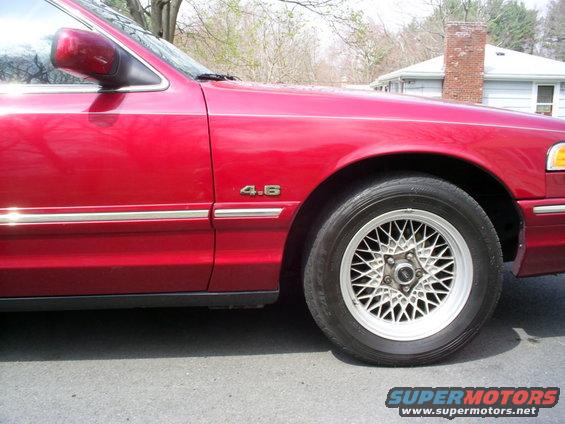 red sedan fender with '4.6' badge and wire-spoke wheel