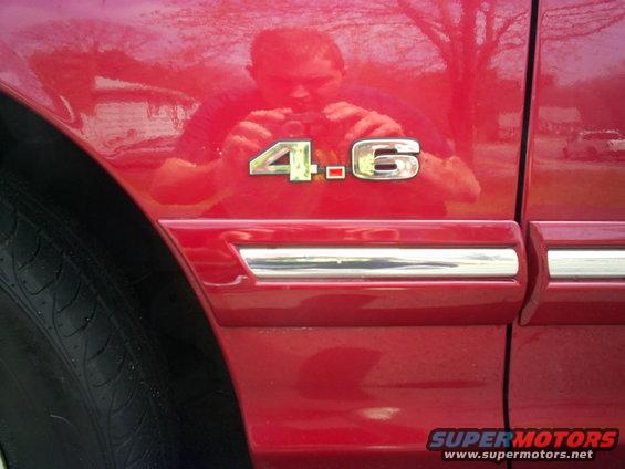 Red 1995 Ford Crown Victoria fender with '4.6' emblem and chrome trim