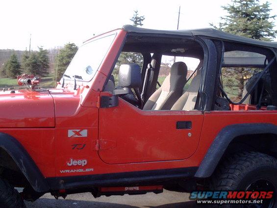 Red Jeep Wrangler TJ side view, showing doors and interior. "TJ" and "Jeep Wrangler" badges visible