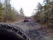 1991 Ford Bronco - A convoy of Jeeps navigates a wooded dirt road, with the foreground dominated by the tire of the lead vehicle.
