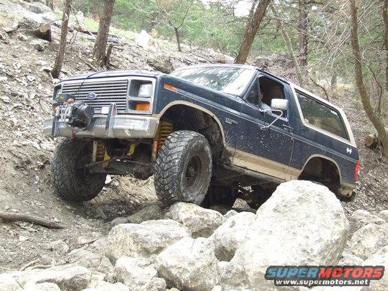 Dark blue Ford Bronco on rocks, looks like an 80s model