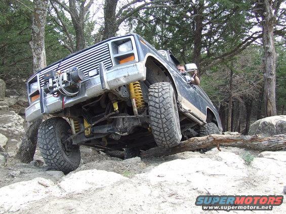 Modified off-road vehicle with winch on front bumper navigating rocky terrain