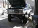 1994 Ford Bronco - The front of a lifted Ford Bronco is shown with its hood open, revealing the engine compartment and a prominent grille.