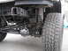 1994 Ford Bronco - Close-up view of the rear axle and suspension system on a lifted vehicle, an off-road tire.