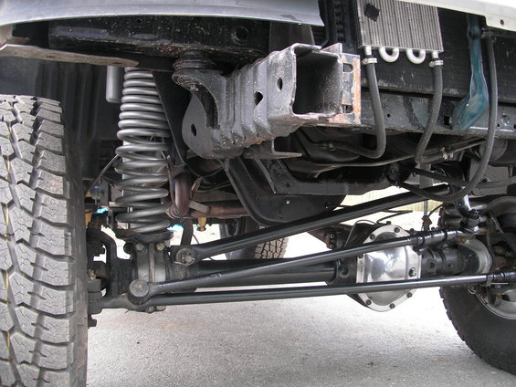 Close-up of front axle, coil spring suspension, and steering linkage on a vehicle