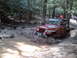 1991 Ford Bronco - This Jeep is deep in the mud, with a second vehicle visible further down the trail.