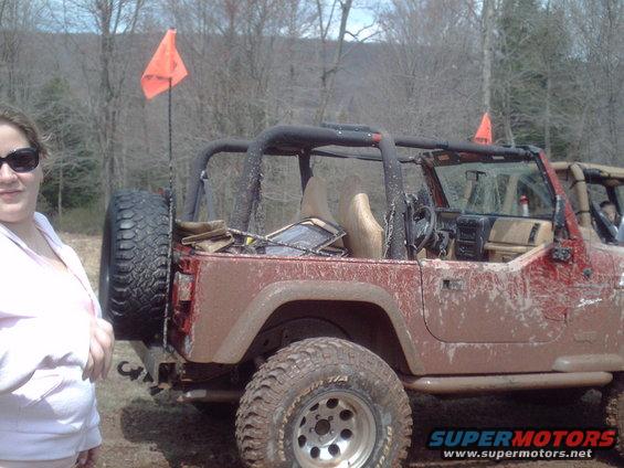 Red Jeep Wrangler with orange flags, spare tire on rear
