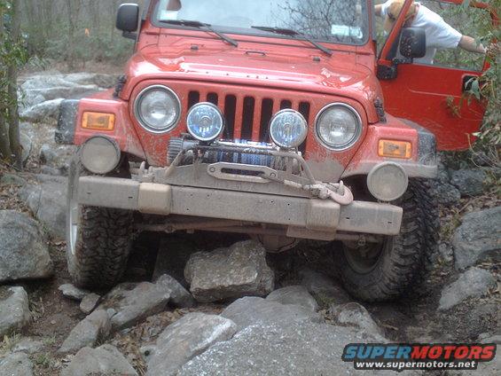 Red Jeep Wrangler navigating a rocky trail with a winch on the front bumper