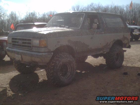 Mud-covered Ford Bronco with large tires, seen from the front-right
