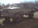 1991 Ford Bronco - A muddy Ford Bronco is parked off-road with other vehicles in the background.
