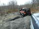 1991 Ford Bronco - A line of Jeeps navigates a rough, gravelly trail through a wooded area.