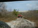 1991 Ford Bronco - An orange Jeep Wrangler navigates a rocky dirt path, with another vehicle following closely behind.