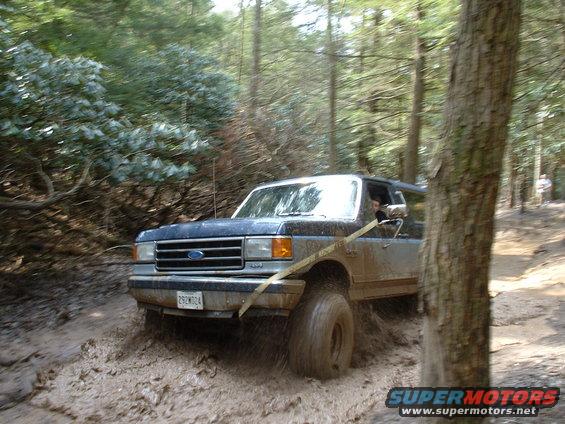 Blue 1991 Ford Bronco navigating a muddy trail