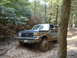 1991 Ford Bronco - A blue 1991 Ford Bronco tackles a challenging muddy off-road course.