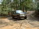 1991 Ford Bronco - This 1991 Ford Bronco navigates a challenging muddy path in a wooded area.