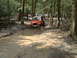 1991 Ford Bronco - Multiple Jeep Wranglers tackle a muddy off-road course in a wooded area.