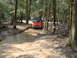 1991 Ford Bronco - Jeep Wrangler navigates a muddy path in a wooded area with another vehicle following.