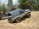 1991 Ford Bronco - A muddy Ford Bronco navigates an off-road trail alongside another vehicle.