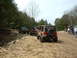 1991 Ford Bronco - Off-road vehicles navigate a dusty trail surrounded by trees, with several people gathered near the vehicles.