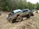 1991 Ford Bronco - A lifted Ford Bronco navigates an off-road trail with other vehicles in the background.