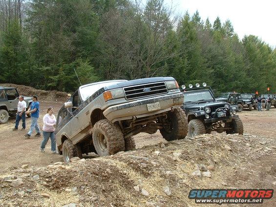 1991 Ford Bronco climbing dirt mound, front grille visible