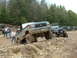 1991 Ford Bronco - A lifted 1991 Ford Bronco navigates an off-road obstacle course with other vehicles in the background.